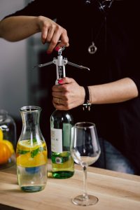 Home kaboompics hands opening wine bottle with corkscrew 2981