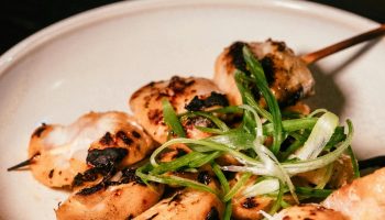 Delicious grilled chicken skewers with green onions on a ceramic plate, perfect for a delightful meal.